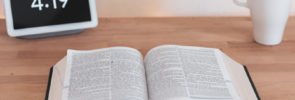 Bible on desk with cup and clock
